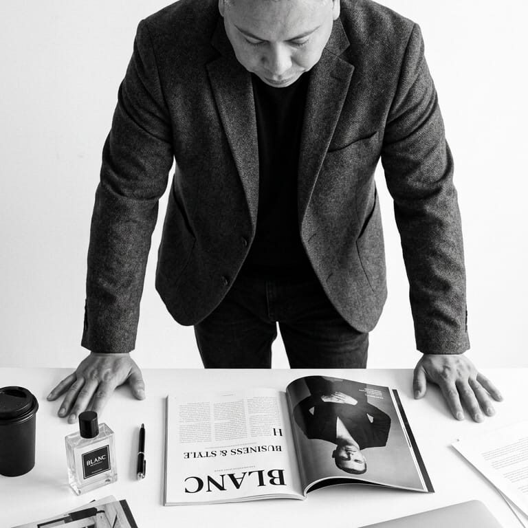 Moody portrait of an adult man in a black suit and white shirt against a dark background.